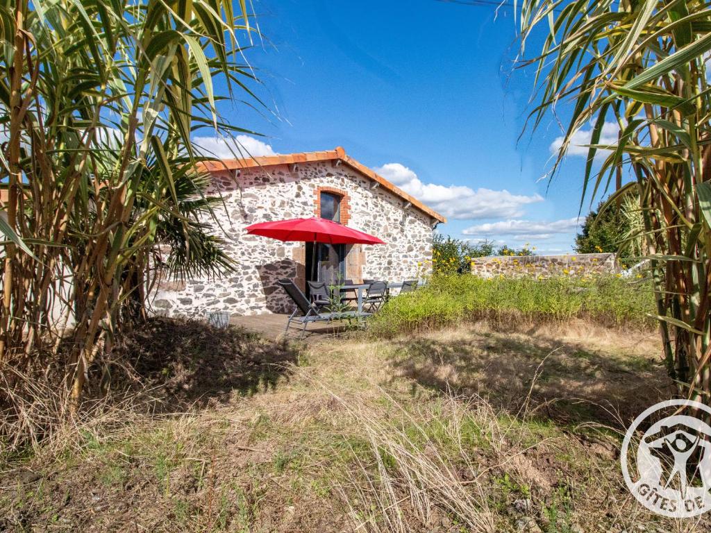 a building with a red umbrella in front of it at Gîte Moderne et Confortable Proche Cholet, Nantes et Puy du Fou, avec Terrasse et Près d'un Étang - FR-1-622-43 in La Renaudière