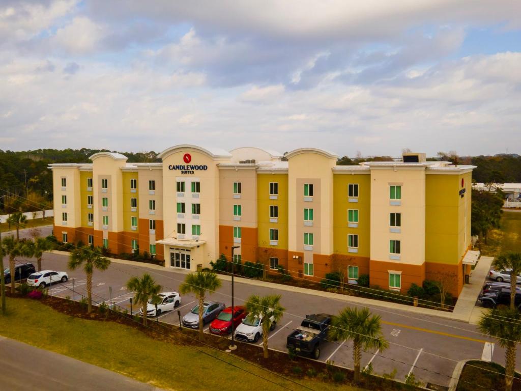 Un gran edificio amarillo con autos estacionados en un estacionamiento. en Candlewood Suites - Panama City Beach Pier Park by IHG, en Panama City Beach
