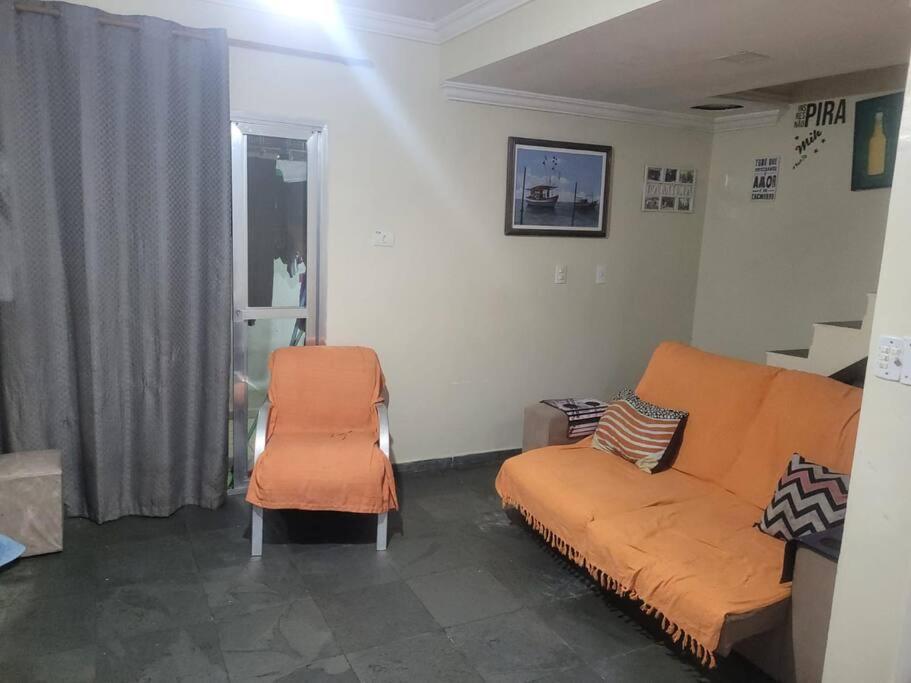 a living room with an orange couch and a chair at Casa Tomazella in Guarujá