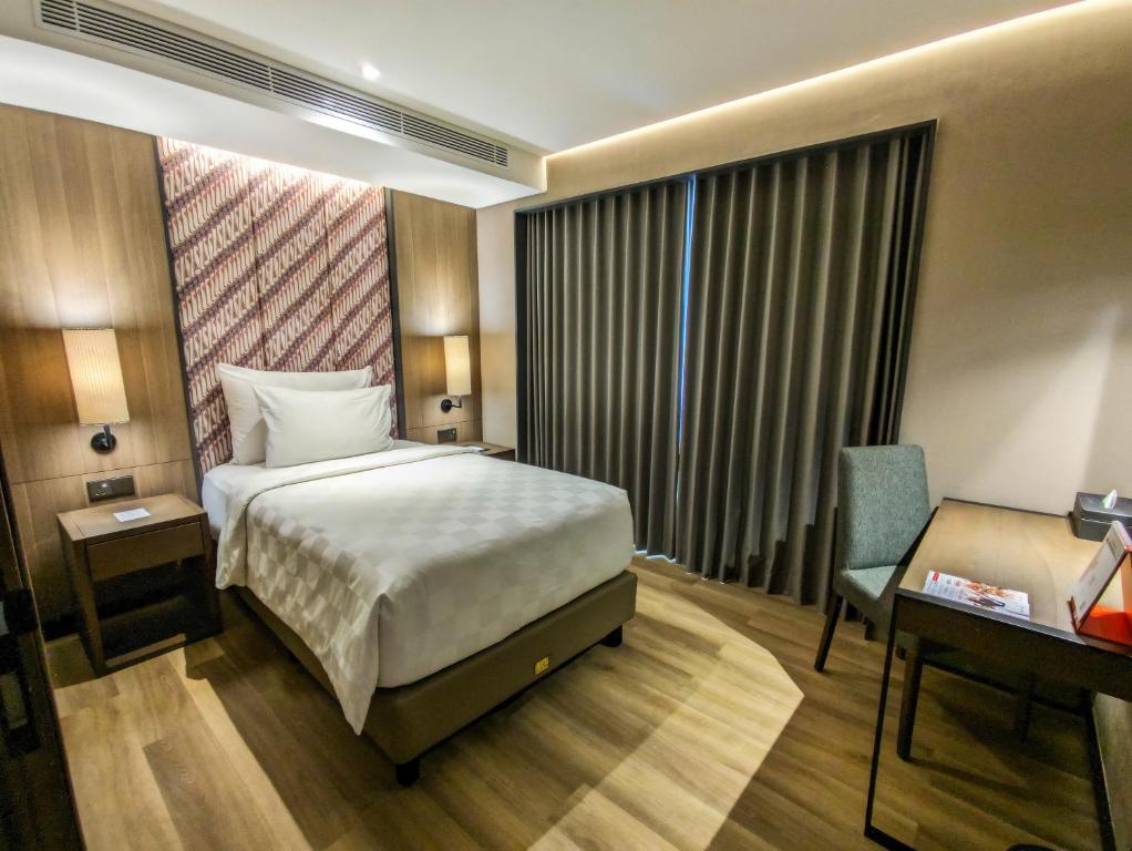 a hotel room with a bed and a desk at Swiss-Belhotel Airport Yogyakarta in Yogyakarta
