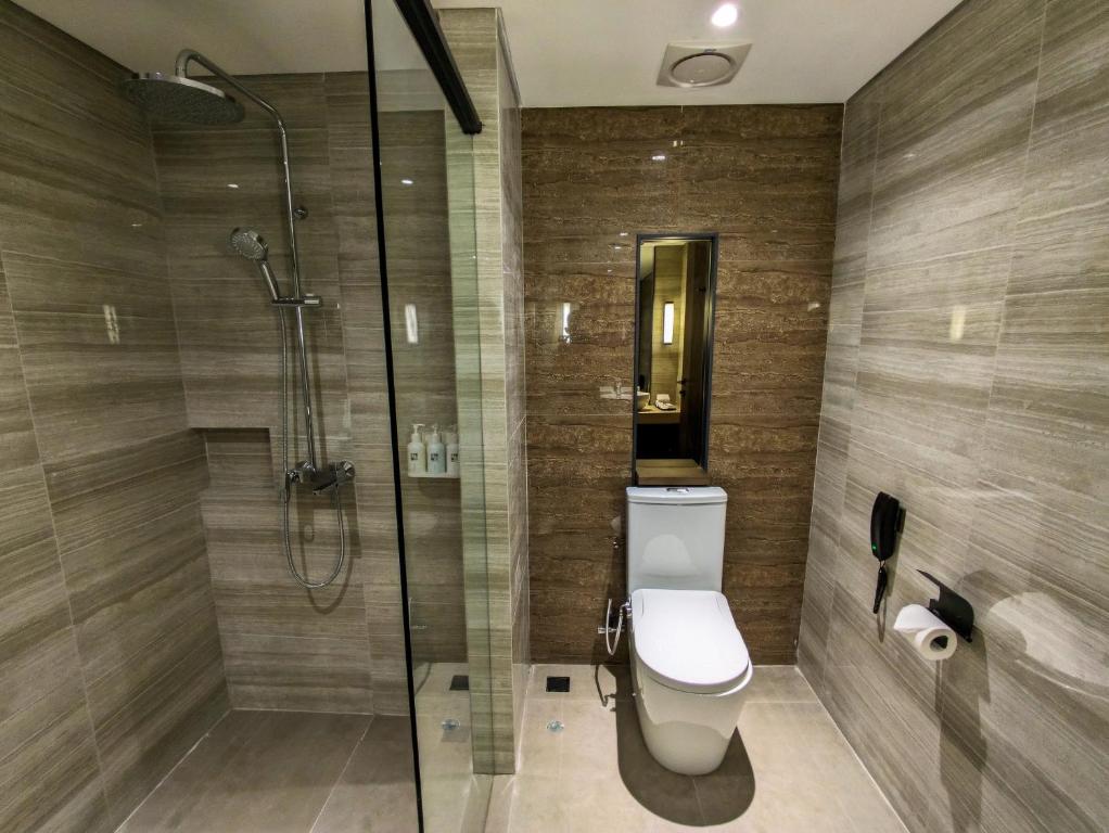 a bathroom with a toilet and a glass shower at Swiss-Belhotel Airport Yogyakarta in Yogyakarta