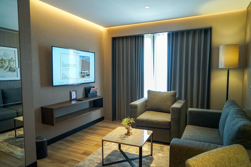 a living room with a couch and chair and a tv at Swiss-Belhotel Airport Yogyakarta in Yogyakarta