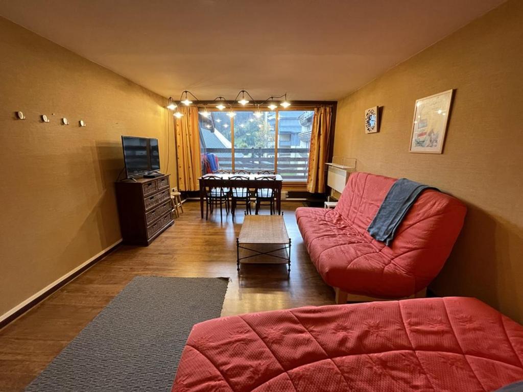 - un salon avec un canapé rouge et une salle à manger dans l'établissement Appartement cosy avec balcon au cœur de la station - FR-1-787-78, à Laveissière