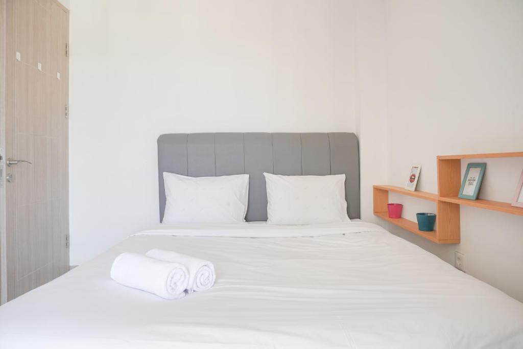 RawalembangGood Price and Nice 2BR Tokyo Riverside PIK 2 Apartment By Travelio的卧室里有一张白色的大床，床上放着毛巾