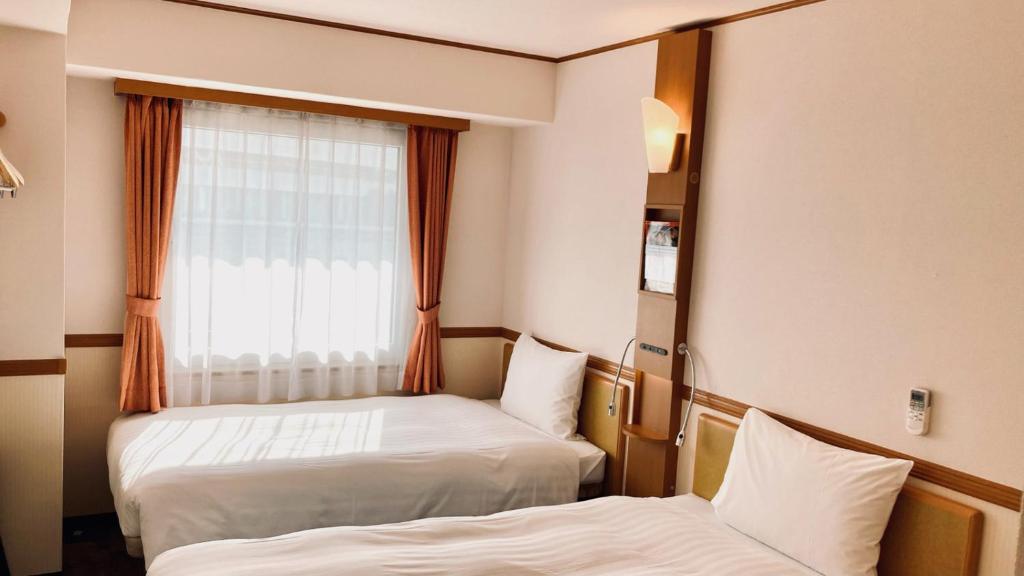 a hotel room with two beds and a window at Toyoko Inn Saitama Shintoshin in Saitama