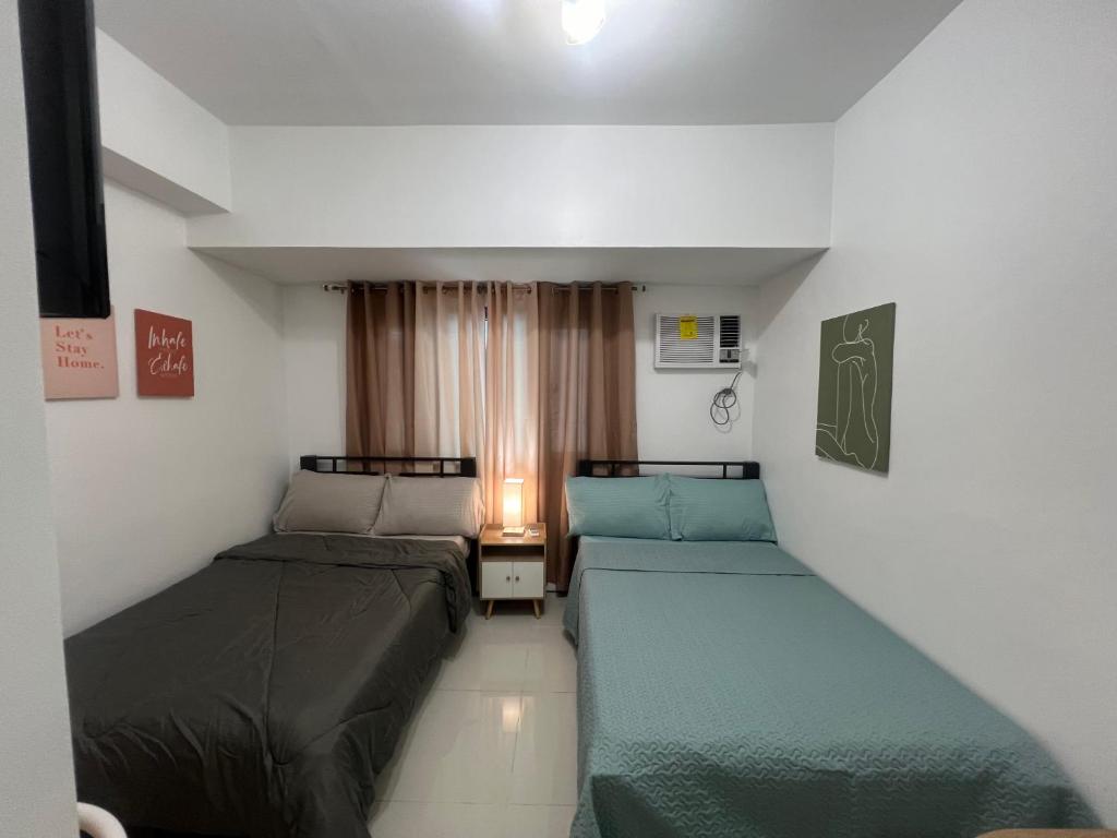 une petite chambre avec deux lits et une fenêtre dans l'établissement Condo In front of US Embassy Studio Unit with 2 Double Beds, à Manille