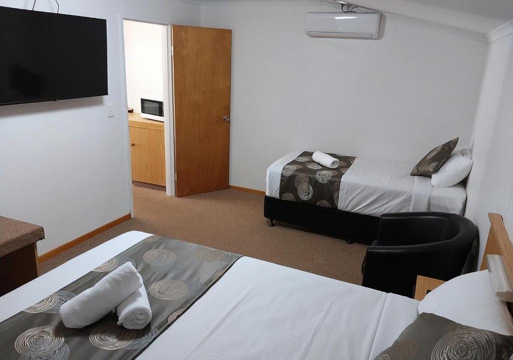 a hotel room with two beds and a flat screen tv at Blue Shades Motel in Maryborough