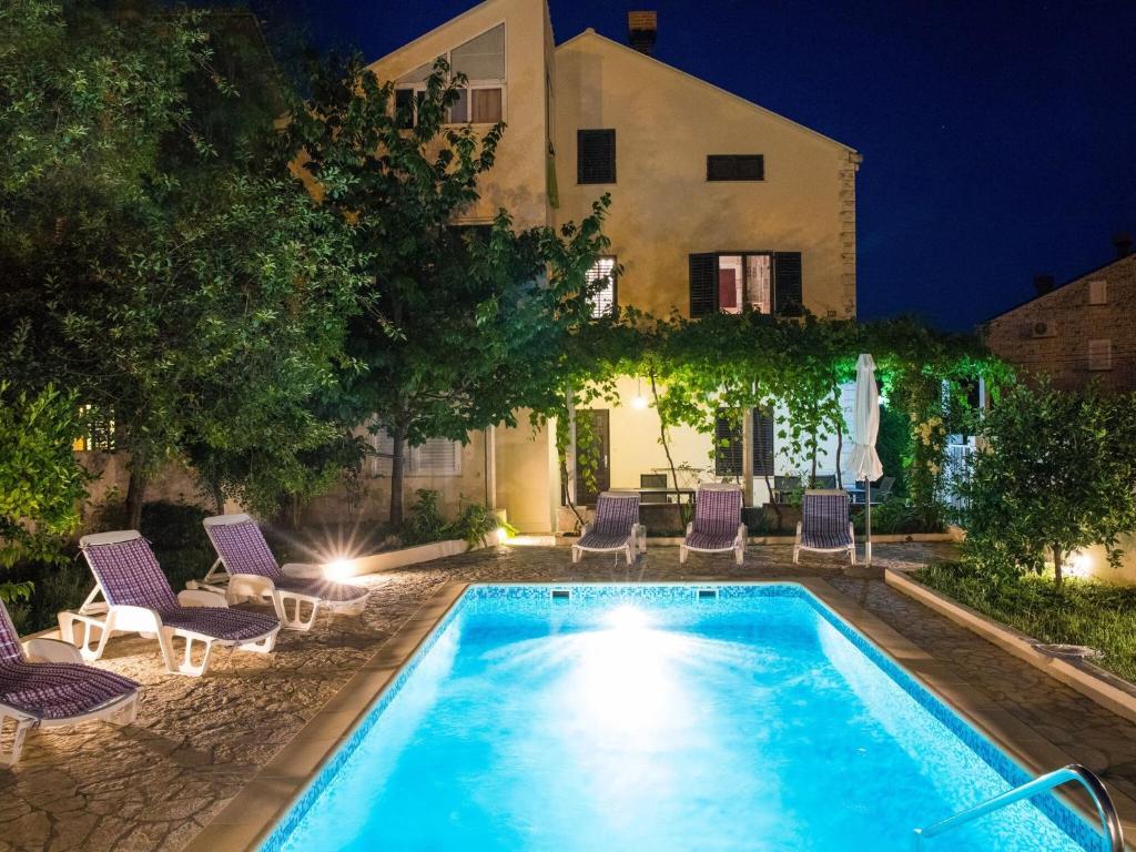 ein Pool mit Stühlen und ein Haus in der Nacht in der Unterkunft Villa Roza - One-Bedroom Apartment with Balcony in Mokošica