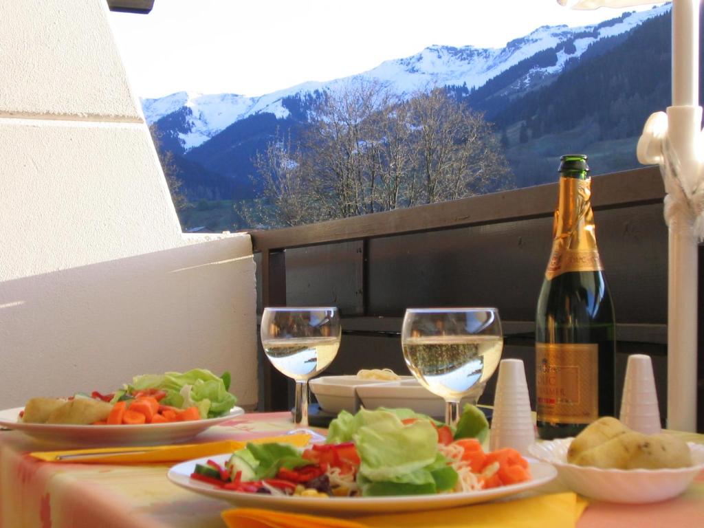 a table with plates of food and glasses of wine at Maria Alm Studio Apartment in Maria Alm am Steinernen Meer