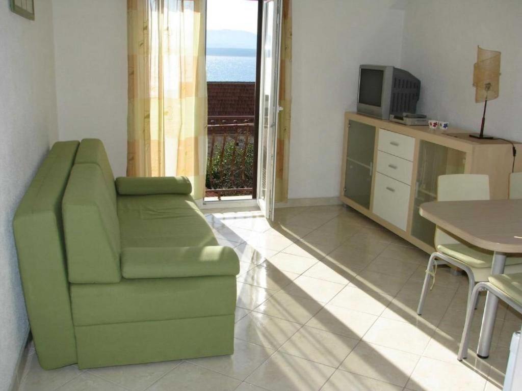 a living room with a green chair and a table at Apartments Paloc - Standard One-bedroom Apartment with Balcony uti in Bol