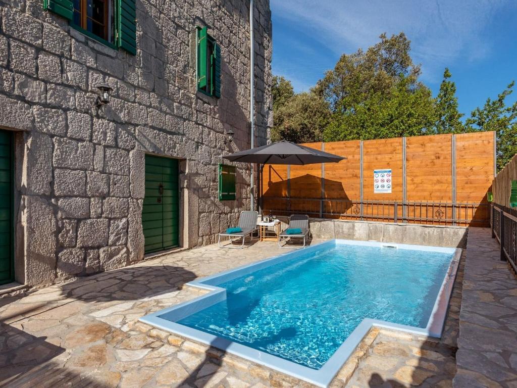 ein Swimmingpool mit Sonnenschirm neben einem Gebäude in der Unterkunft Villa Lazini Dvori - Two Bedroom Stone House Villa with Private Pool in Staševica