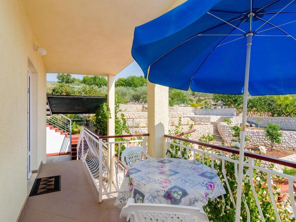 a patio with a blue umbrella and a table and chairs at Apartments Ra ica Molunat - Basic Studio in Molunat