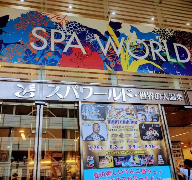 a store front of a spa new world sign at 301号室駅2分格安和室民泊専用ミニキッチンとバスルーム付きアクセス抜群 in Osaka