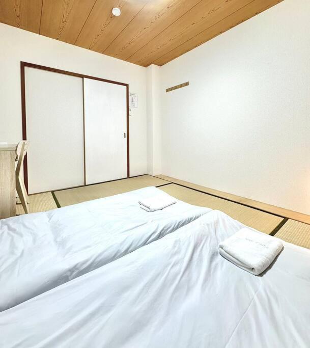 a white bed in a room with a window at 301号室駅2分格安和室民泊専用ミニキッチンとバスルーム付きアクセス抜群 in Osaka