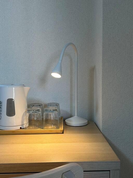 a lamp sitting on top of a wooden table with glasses at 301号室駅2分格安和室民泊専用ミニキッチンとバスルーム付きアクセス抜群 in Osaka