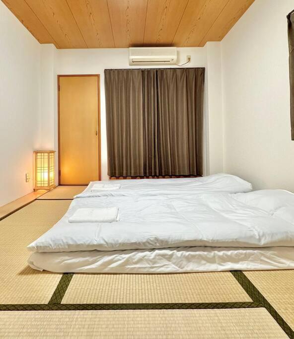 a large white bed in a room with a window at 301号室駅2分格安和室民泊専用ミニキッチンとバスルーム付きアクセス抜群 in Osaka