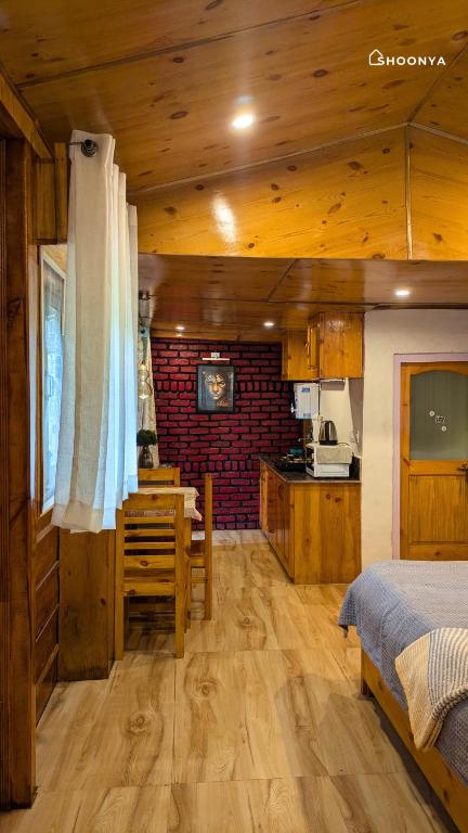 a bedroom with a bed and a table and a kitchen at Shoonya Mukteshwar in Mukteswar