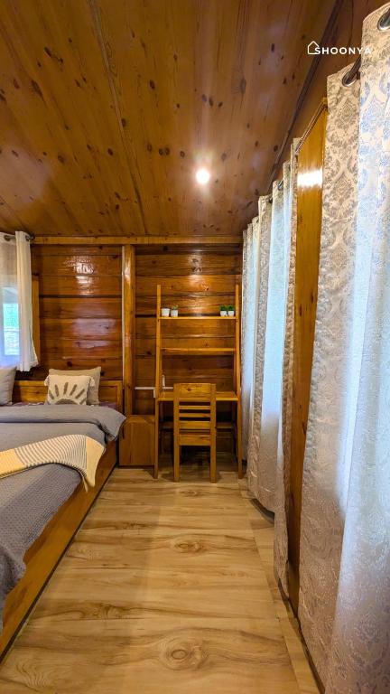 a room with two beds and a table in a cabin at Shoonya Mukteshwar in Mukteswar