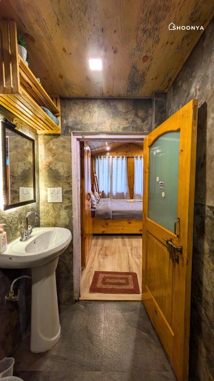 a bathroom with a sink and a toilet and a door at Shoonya Mukteshwar in Mukteswar