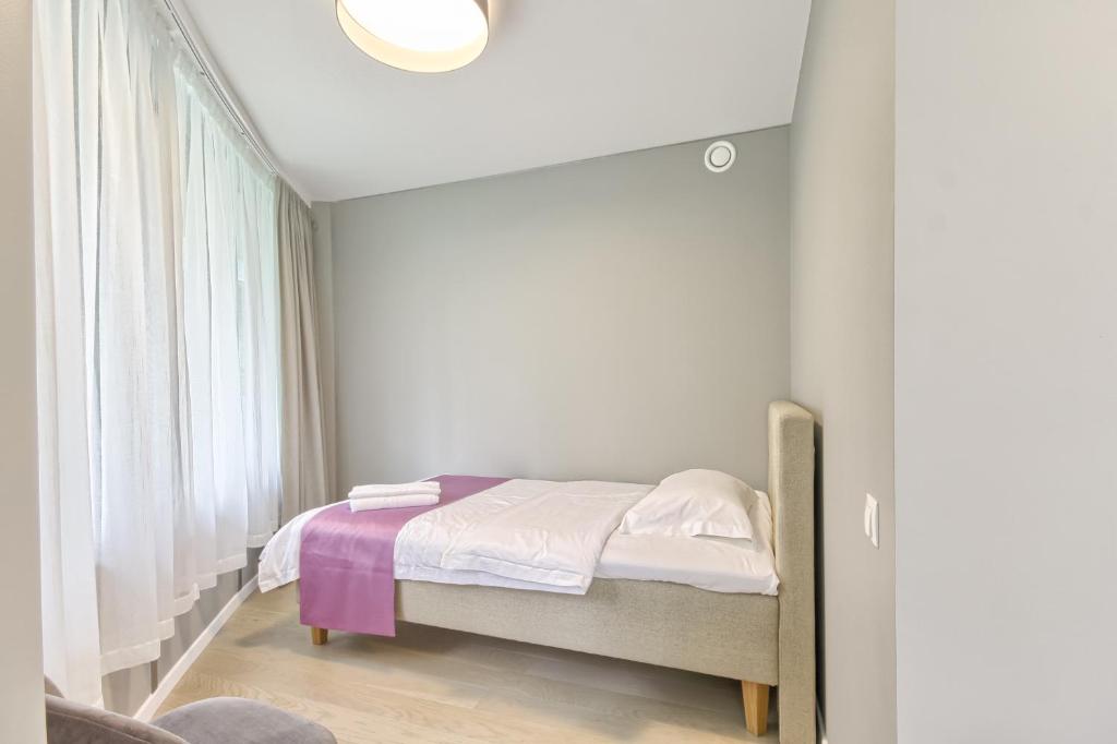 a small bedroom with a bed with a window at Asian Magnolia Express Studio Apartments in Druskininkai