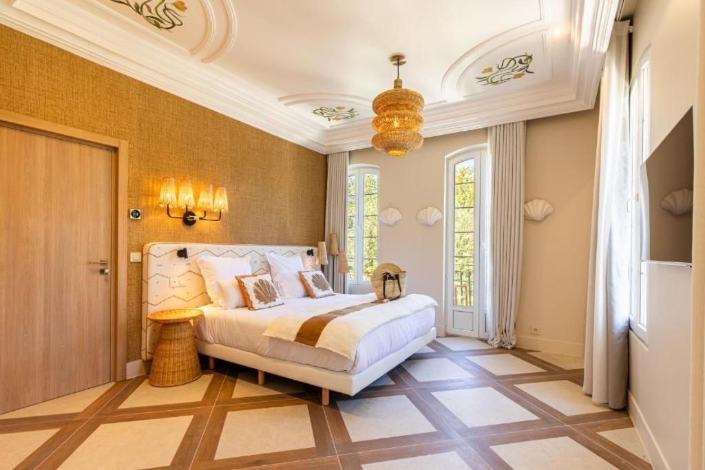 een slaapkamer met een bed en een kroonluchter bij Le clos de la pinède chambre Deluxe 300 e par chambre in Saint-Tropez