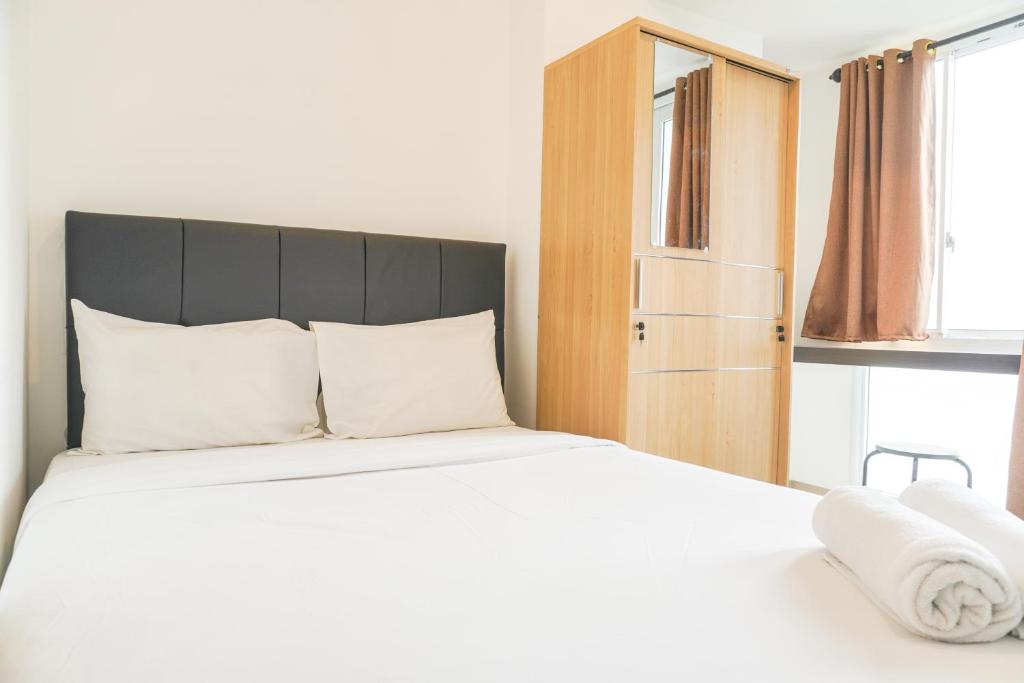 ein Schlafzimmer mit einem großen Bett und weißen Kissen in der Unterkunft Comfortable and Well Design Studio Tokyo Riverside PIK 2 Apartment By Travelio in Rawalembang