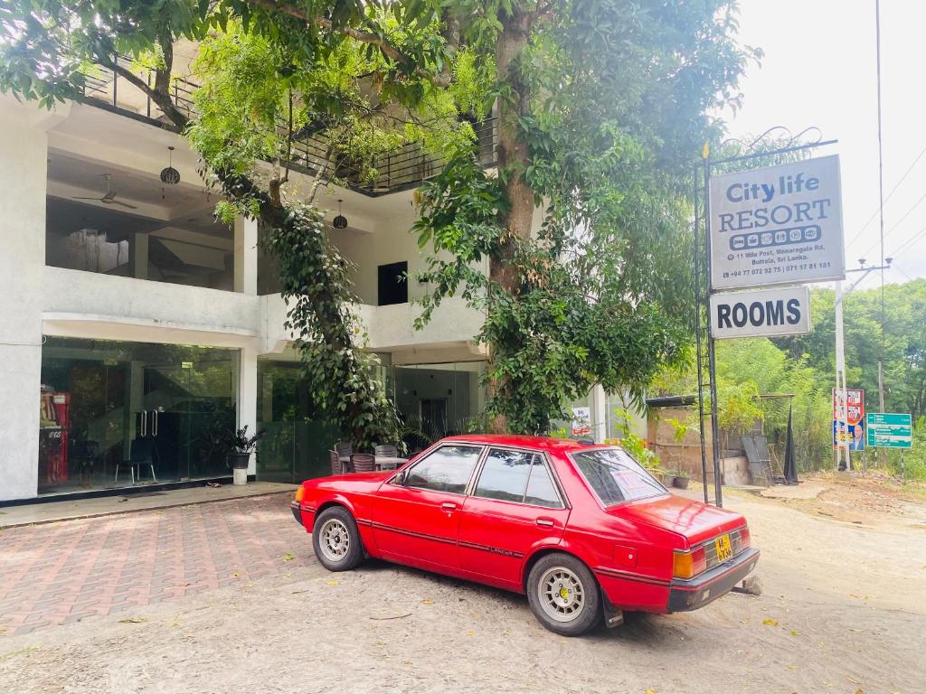 a red car parked in front of a building at City Life Hotel and Restaurant in Buttala