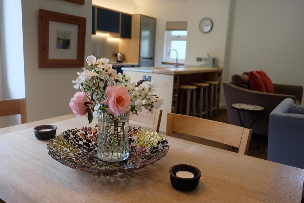 een vaas met bloemen op een tafel bij The Coach House at Hoods Croft in Lewes