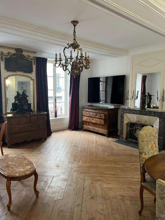 un grand salon avec un lustre et une cheminée dans l'établissement Le royal, F2 en centre-ville, à Bayeux