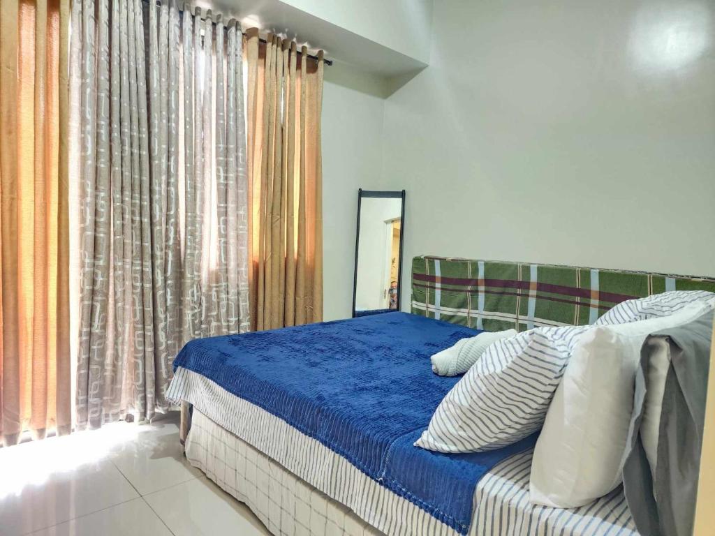 バギオにある1 Bed Flat - Pool - Parking - Wifiのベッドルーム1室(青いシーツと鏡付きのベッド1台付)
