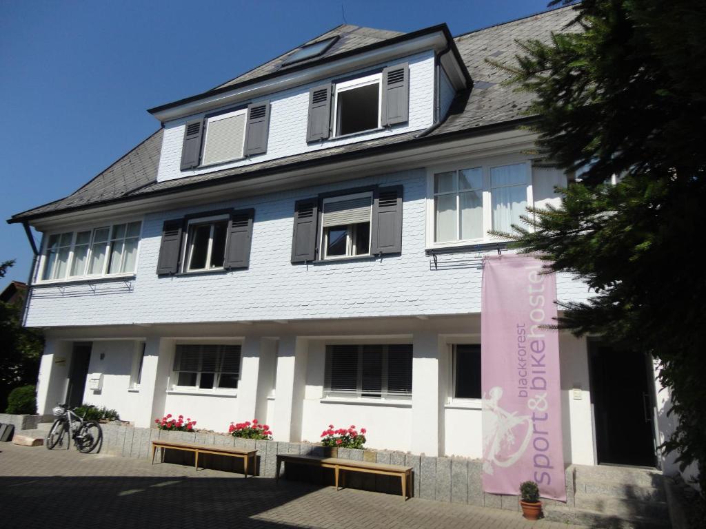 a white building with a pink banner in front of it at Black Forest Bike Hostel in Kirchzarten
