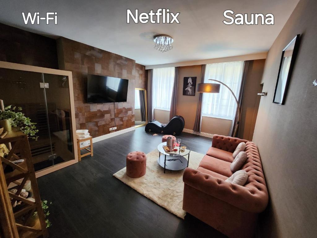 a living room with a couch and a tv at Love Room l'Audacieuse in Saint-Quentin