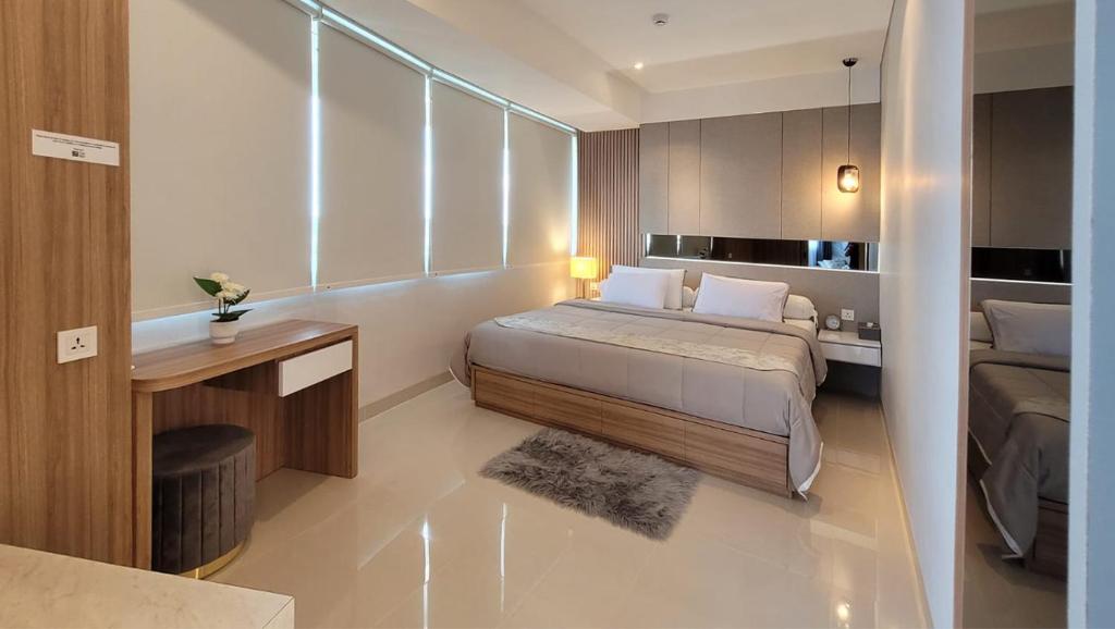 a bedroom with a bed and a desk in a room at Apartment Nuvasa Bay Nongsa, Kalani 1BR 8th, Sea & Golf View, Batam in Nongsa