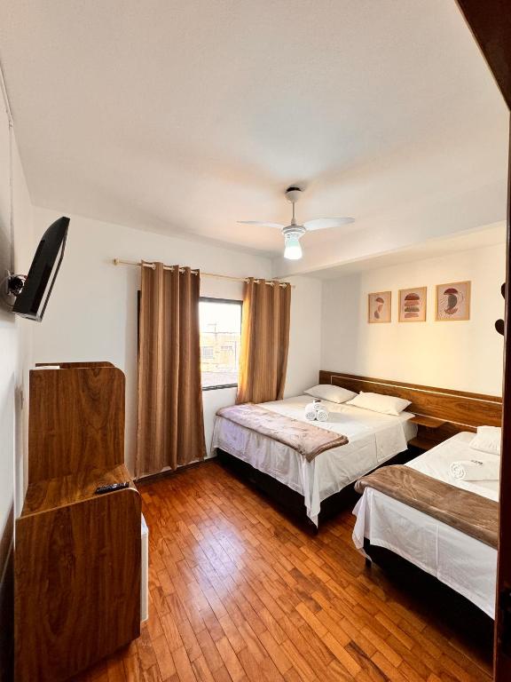 a hotel room with two beds and a window at Hotel Real Cruzilia in Cruzília
