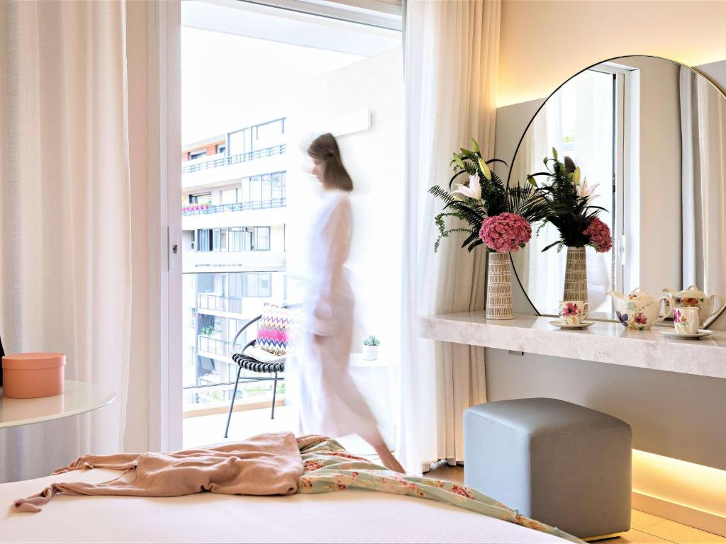 a woman walking out of a window in a room at Croisette Beach Hotel Cannes - MGallery Collection in Cannes