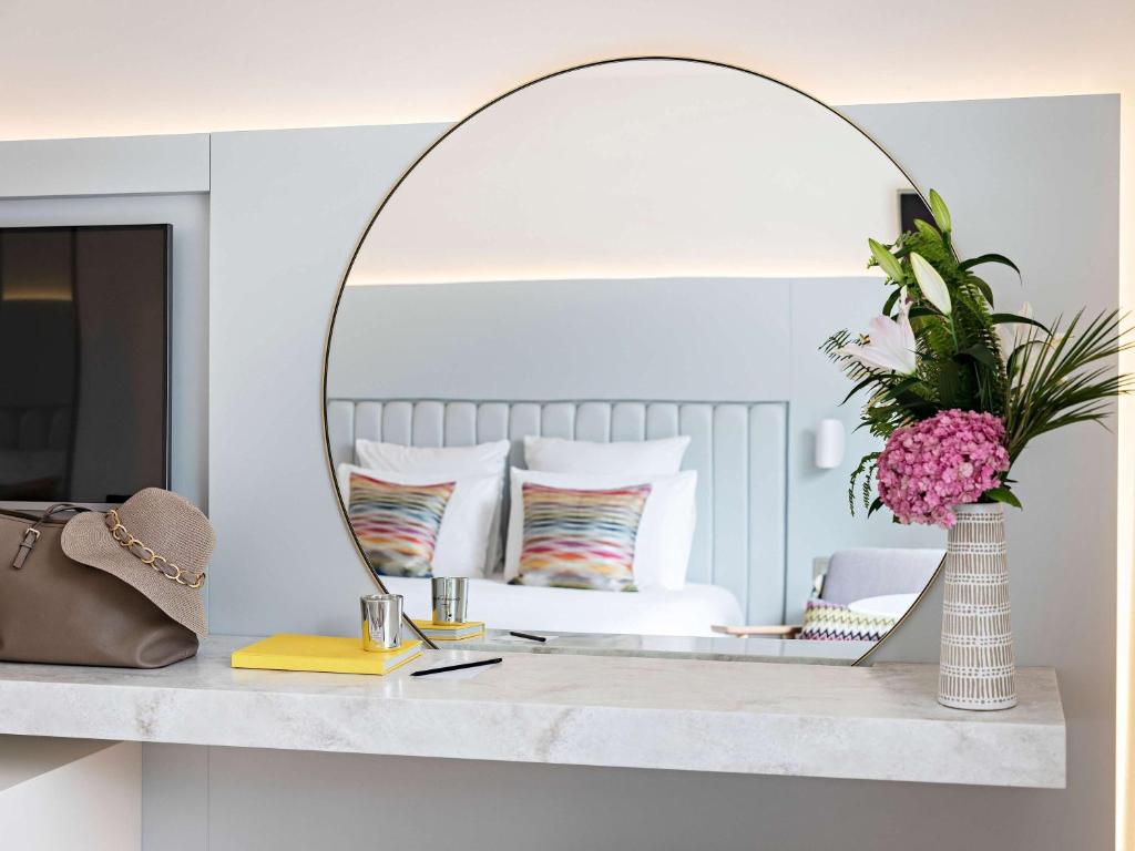 a mirror on a counter in a room with a bed at Croisette Beach Hotel Cannes - MGallery Collection in Cannes