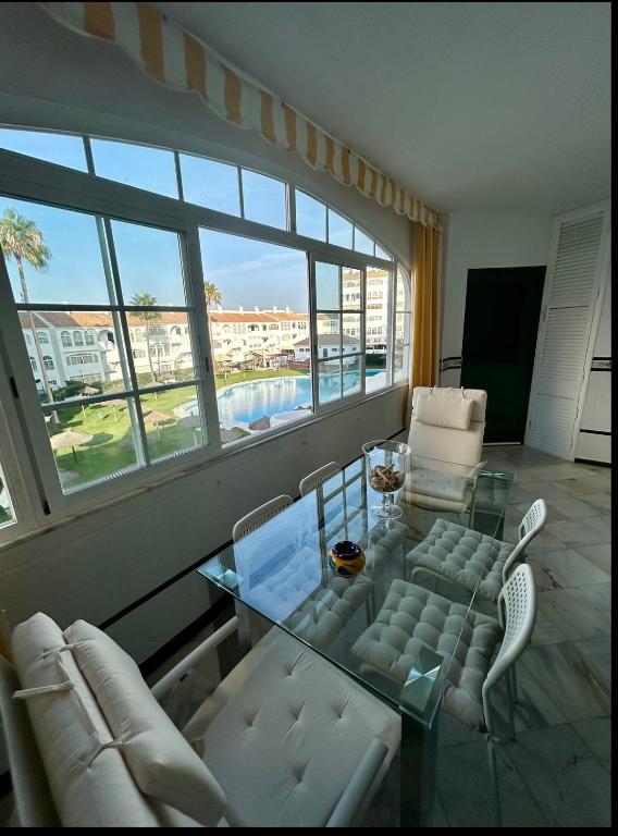 a living room with a glass table and white chairs at Apto Laguna con piscina in El Portil