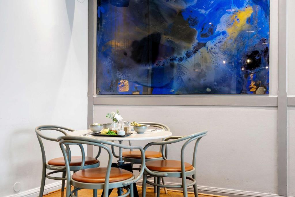 a table with four chairs and a painting on the wall at Best Western Plus Park City Solna in Solna