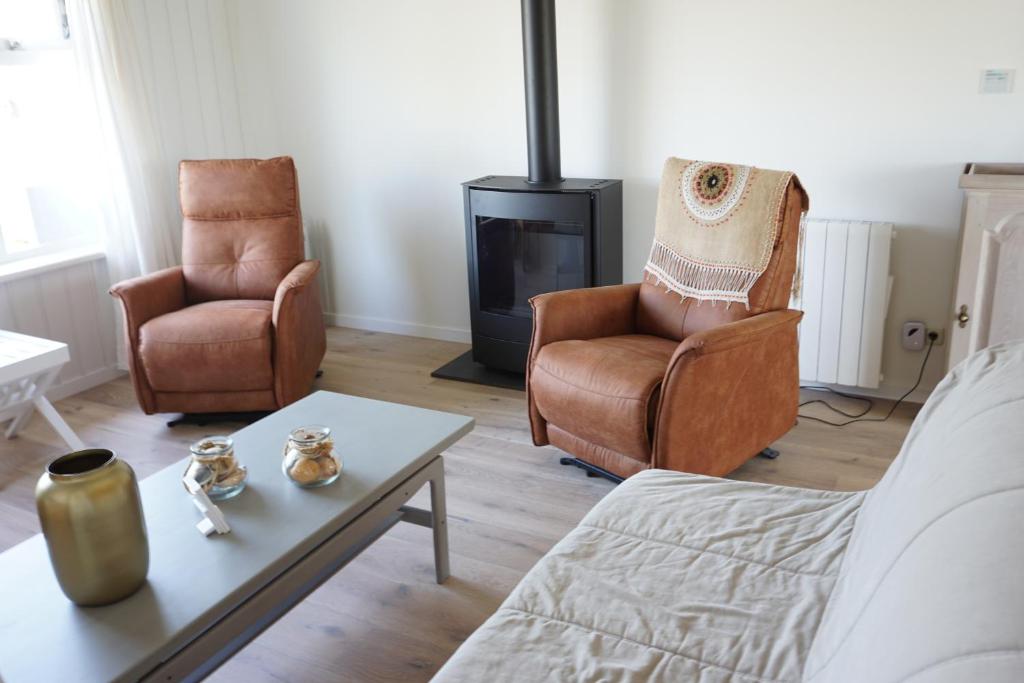 a living room with two chairs and a fireplace at Kustverhuur, Huuske Groede, pittoresk huisje vlakbij zee in Groede