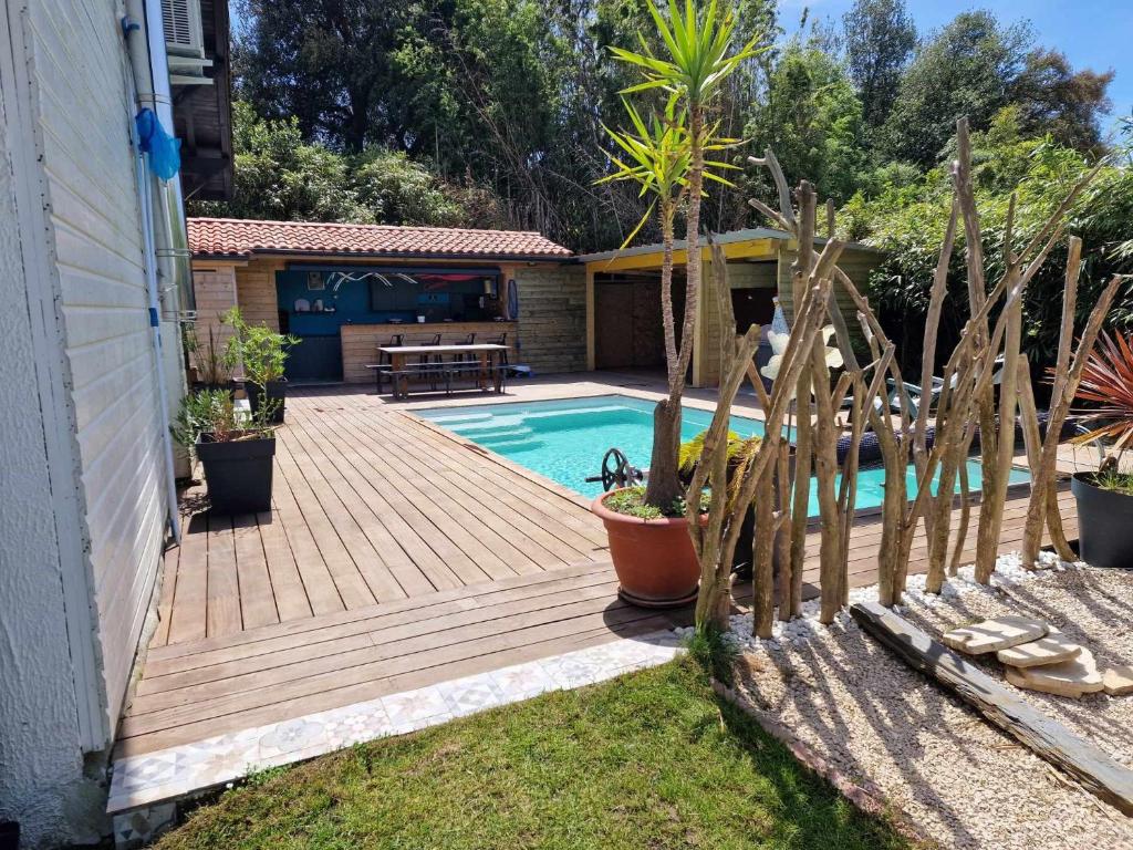 une terrasse en bois à côté d'une maison avec une piscine dans l'établissement Villa avec piscine à proximite de la plage 10 pers, à Ondres