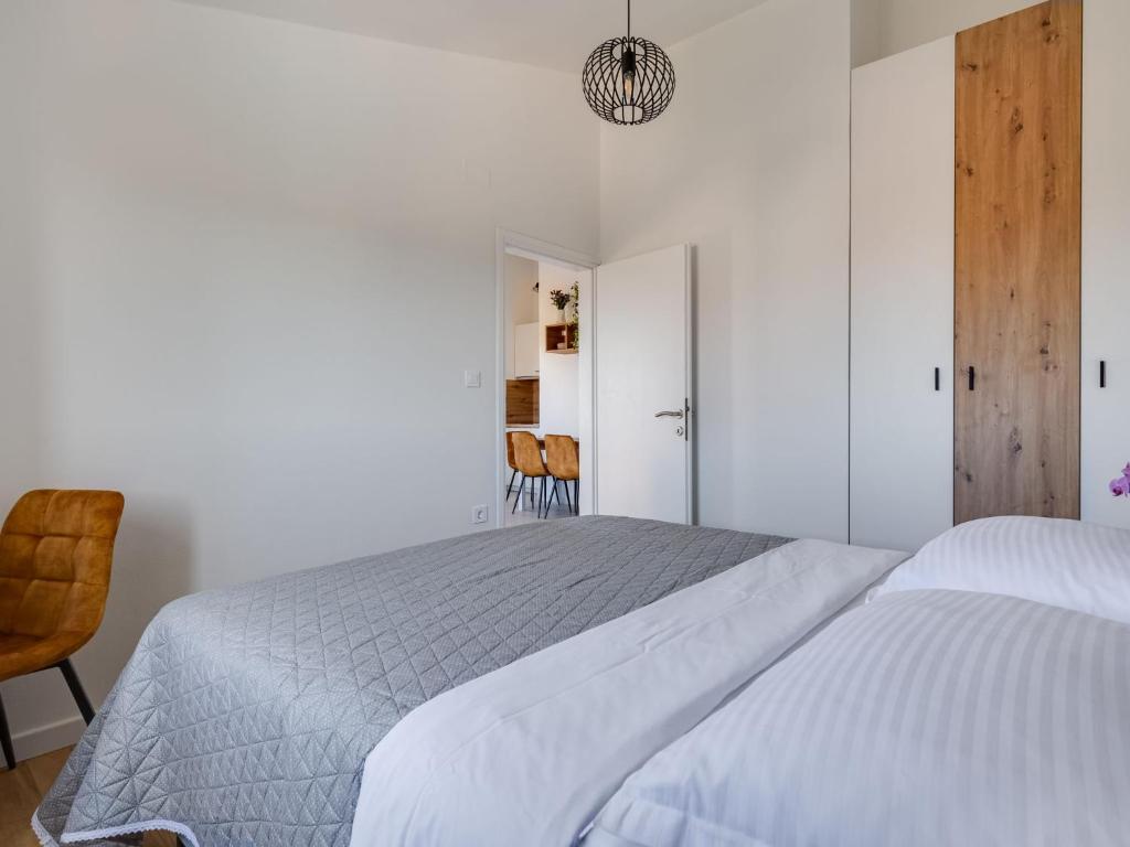biała sypialnia z 2 łóżkami i krzesłem w obiekcie Apartment Bonex-7 by Interhome w mieście Privlaka