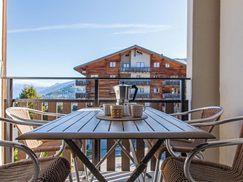 a table on a balcony with a coffee maker on it at Apartment Genets 150 D by Interhome in Nendaz