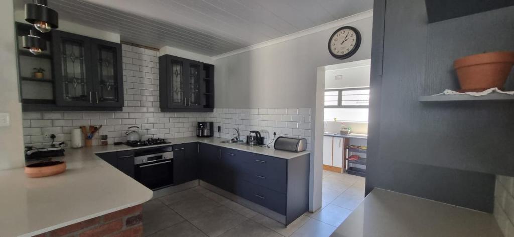ケープタウンにあるFamily holiday home to rentのシンクと壁に時計が付いたキッチン