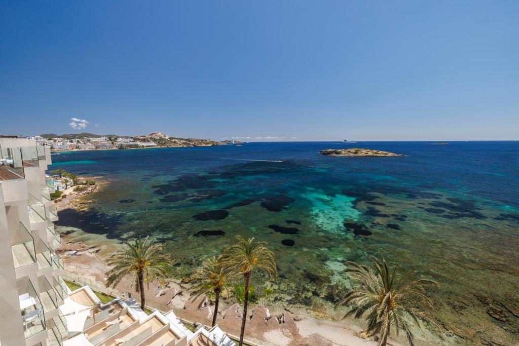 an aerial view of a beach with palm trees and the ocean at Hotel Torre del Mar - Ibiza in Playa d'en Bossa