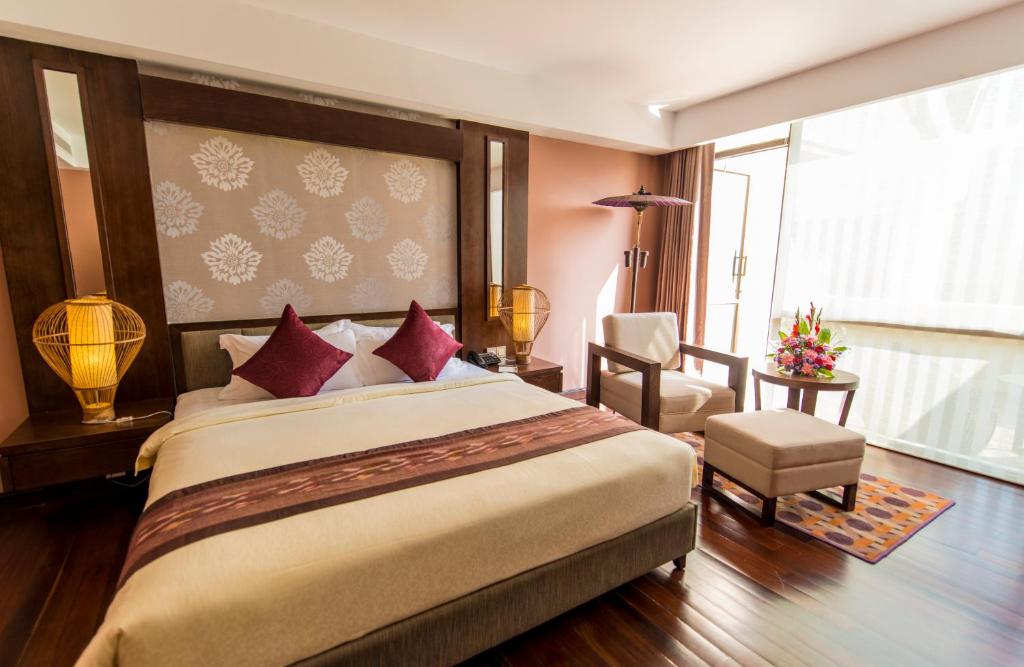 a hotel room with a large bed and a chair at Rose Garden Hotel in Yangon