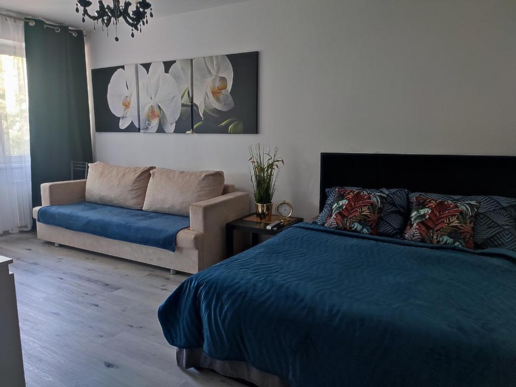 a bedroom with a blue bed and a couch at Apartament Lux2 Konin NOCLEGI in Konin