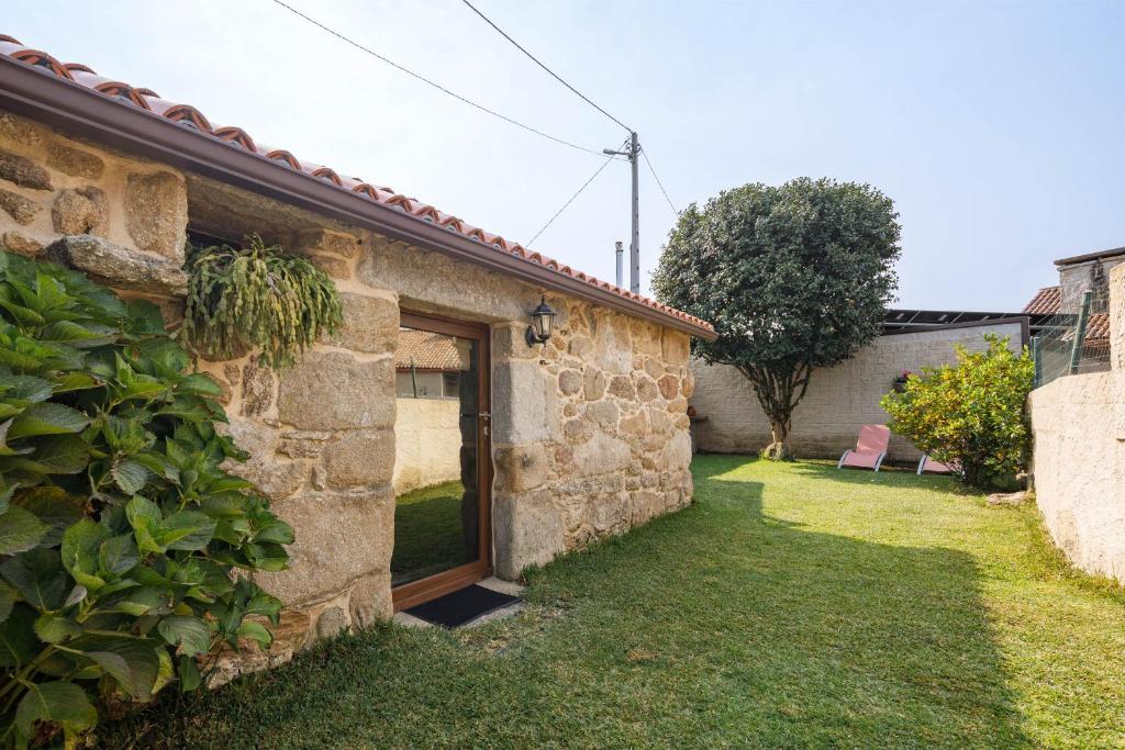 una vista esterna di una casa in pietra con cortile di Casa Rural Roi a Portas