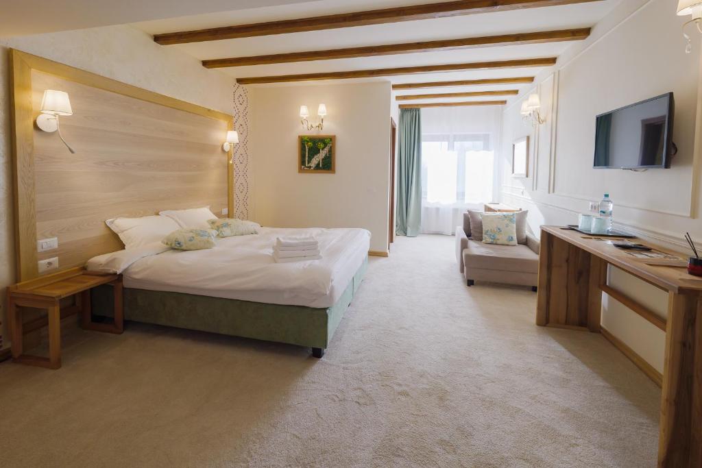 a hotel room with a bed and a television at Crama de Piatra Winery Hotel & Conference Hall in Valea scheilor