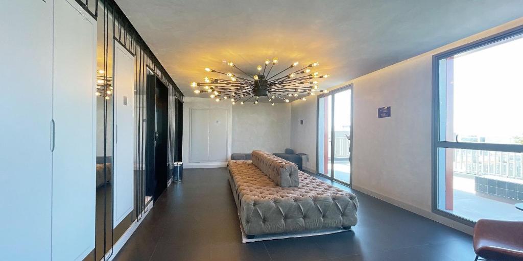un soggiorno con un divano e un lampadario di Condomínio completo, vaga de Garagem e Conforto a 50m do Allianz Parque a San Paolo