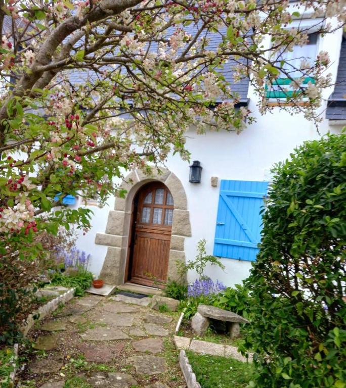 une maison blanche avec une porte bleue et des arbres dans l'établissement Loctudy T2 vintage terrasse vue mer, à Loctudy